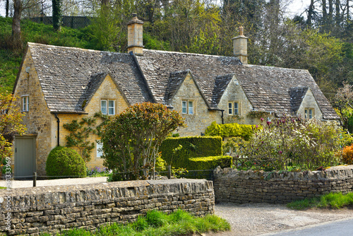 Historic stone house in the Cotwolds of England with front garden and stone fence photo