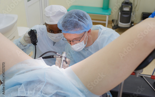 A male doctor performs a colonoscopy operation and examines the rectum of a patient lying on the operating table