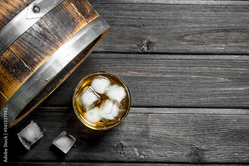 Whiskey in a glass with ice cubes and a barrel. Whiskey in a glass with ice cubes and a barrel.