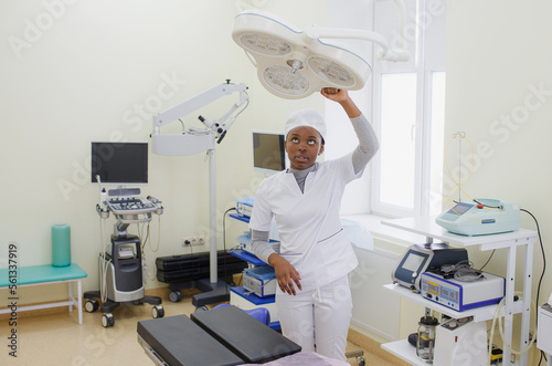 African-American girl doctor adjusts the lighting lamp in the surgery room.