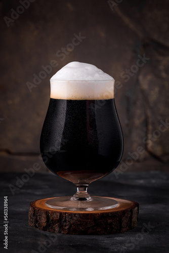 a glass of cold dark beer in a mug on a dark background