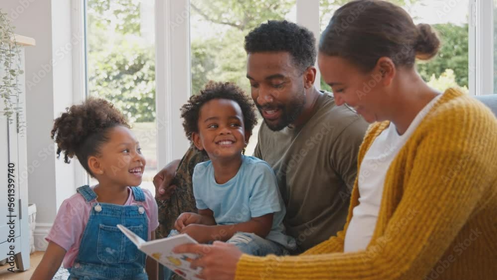 Army Family With Pregnant Mother Sitting On Floor In Lounge At Home Reading Book Together Army Family With Pregnant Mother Sitting On Floor In Lounge At Home Reading Book Together