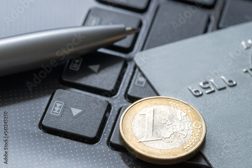 1 euro with credit card MasterCard and pen lying on laptop keyboard