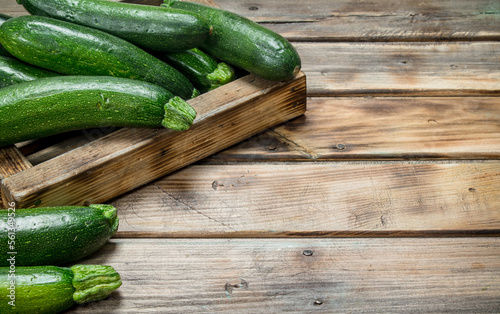 Green zucchini in wooden tray.