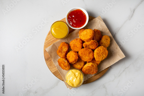 Close up of Chicken crunchy nuggest on plate and sauces dips on light surface