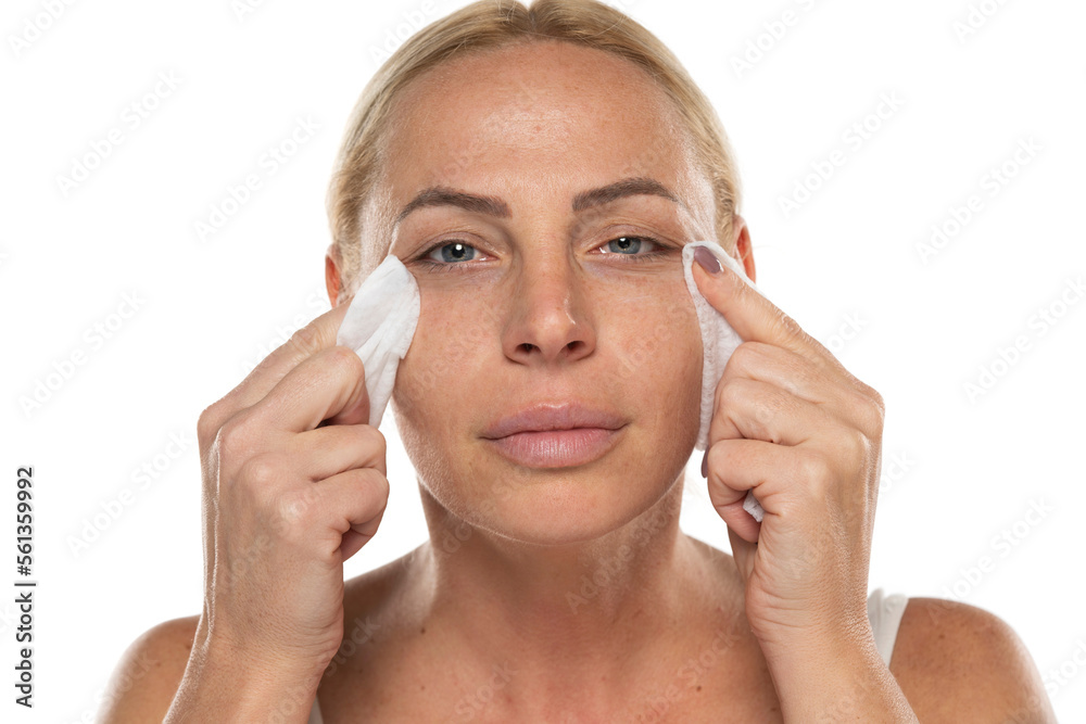 Portrait of a senior woman clean her face with wet tissues on a white background