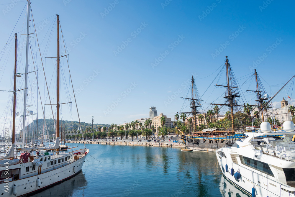 view of the shore of the promenade with yachts boats and palm trees in Spain Barcelona in the city center