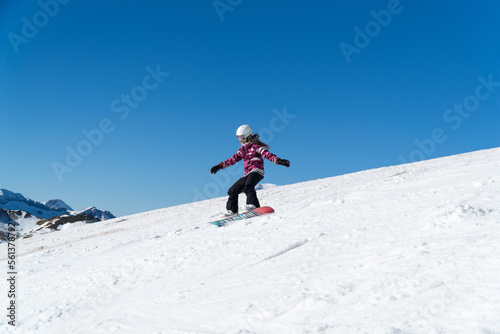 Girl snowboarding in the snow on the mountain on a sunny day