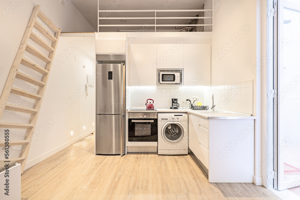 Furnished kitchen of a vacation rental loft with access to a mezzanine with a wooden staircase and access to a terrace with a white aluminum door Furnished kitchen of a vacation rental loft with access to a mezzanine with a wooden staircase and access to a terrace with a white aluminum door