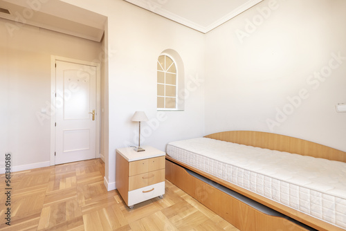 Bedroom with a single cherry wood trundle bed without bedding, with a matching nightstand and oak parquet flooring