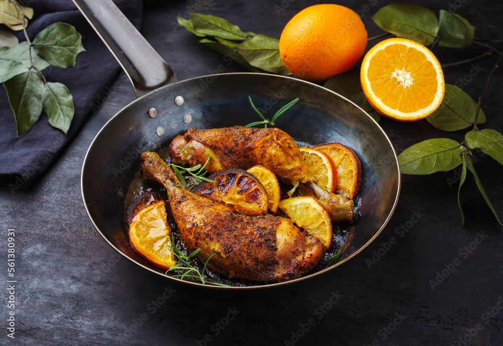 Traditional barbecue chicken drumsticks with orange slices served with herbs as close-up on a rustic metal frying pan Traditional barbecue chicken drumsticks with orange slices served with herbs as close-up on a rustic metal frying pan