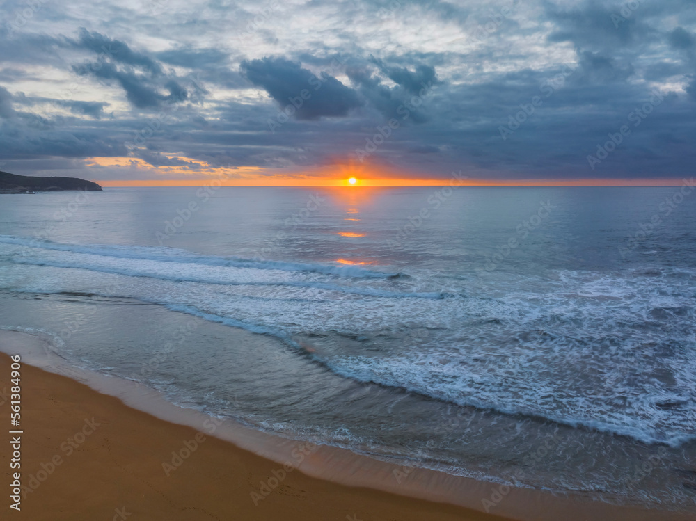 Soft sunrise seascape with clouds and sun on the horizon