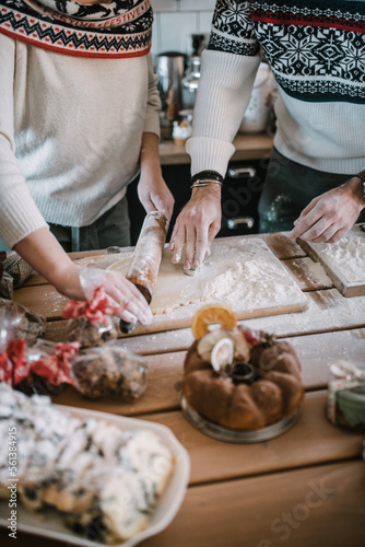 Friends in Christmas sweater baking cookies in kitchen. photo