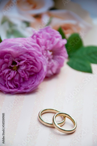 Wedding rings with roses in background, close up photo