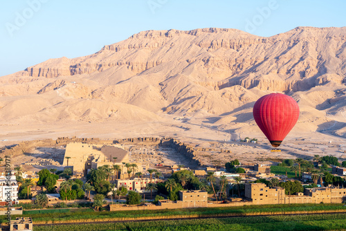Red hot air balloon at sunrise in front of Medinet Habu near the Valley of the Kings in Luxor, Egypt