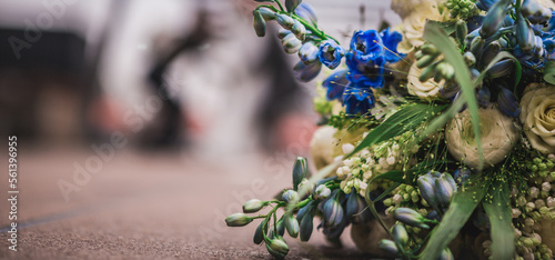 bridal bouquet of mix flowers on a field with a couple in the background bokeh, room for text