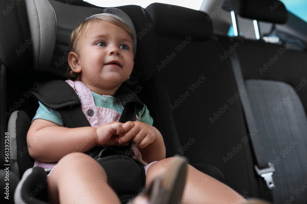Cute little girl sitting in child safety seat inside car Cute little girl sitting in child safety seat inside car
