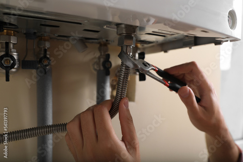 Man repairing gas boiler with waterpump plier, closeup