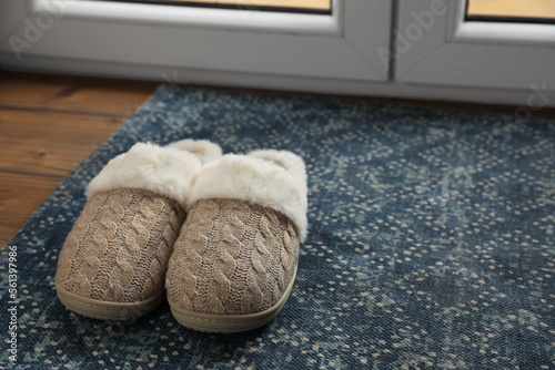 Pair of beautiful soft slippers on mat in room. Space for text