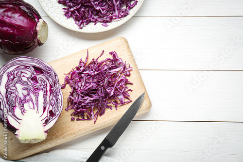 Fresh chopped red cabbage with knife on white wooden table, flat lay. Space for text