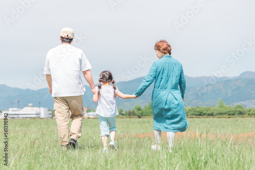 春・夏に公園・草原を歩く家族・ファミリーの後ろ姿（子供・両親・移住・田舎暮らし）  © buritora