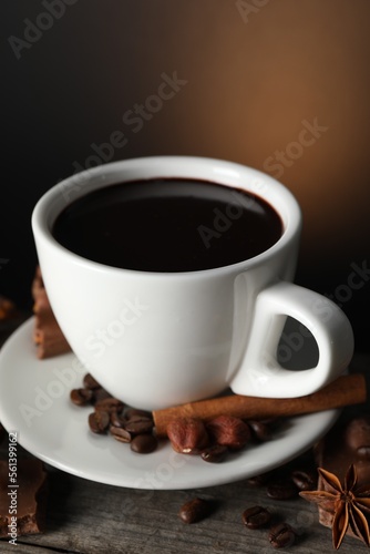 Cup of delicious hot chocolate  spices and coffee beans on wooden table