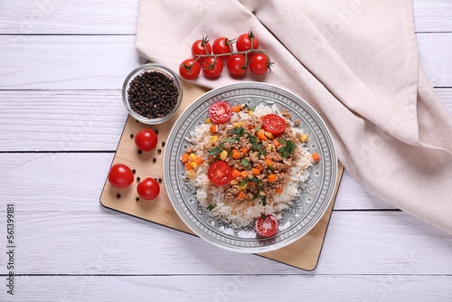 Tasty dish with fried minced meat, rice, carrot, tomatoes and corn on white wooden table, flat lay