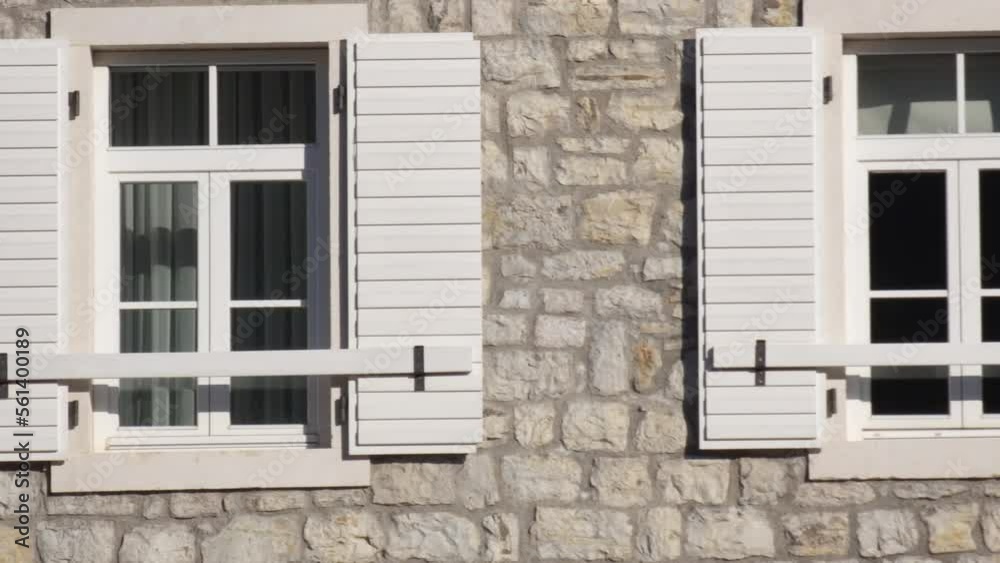 Windows with white wooden shutters on old traditional style stone wall of a house. Windows with white wooden shutters on old traditional style stone wall of a house.