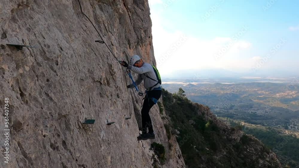 Via ferrata ascension by group of friends . Aerial drone view of mountain and mountaineers climbing in Alicante, Spain. Via ferrata ascension by group of friends . Aerial drone view of mountain and mountaineers climbing in Alicante, Spain.