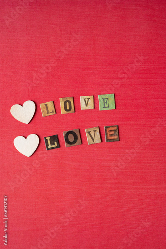 wooden heart shapes and the word "love" repeated twice on red paper