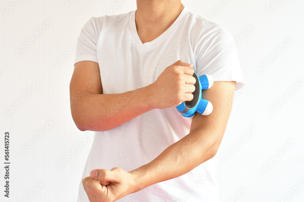 Hombre latino usando un masajeador portatil para aliviar dolor en el brazo. Hombre latino usando un masajeador portatil para aliviar dolor en el brazo.