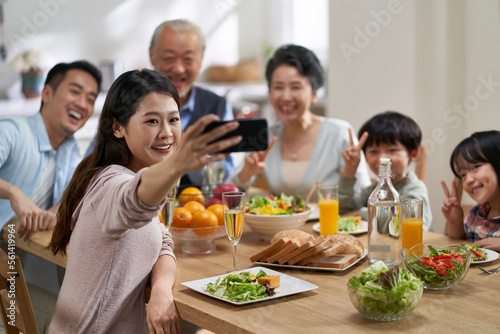 multi generational asian family taking a selfie at dining table