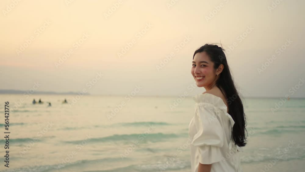 Young Asian woman in white dress walking on the beach during travel tropical island on summer holiday vacation vacation at sunset. Attractive girl relax and enjoy outdoor lifestyle walking at seaside. Young Asian woman in white dress walking on the beach during travel tropical island on summer holiday vacation vacation at sunset. Attractive girl relax and enjoy outdoor lifestyle walking at seaside.