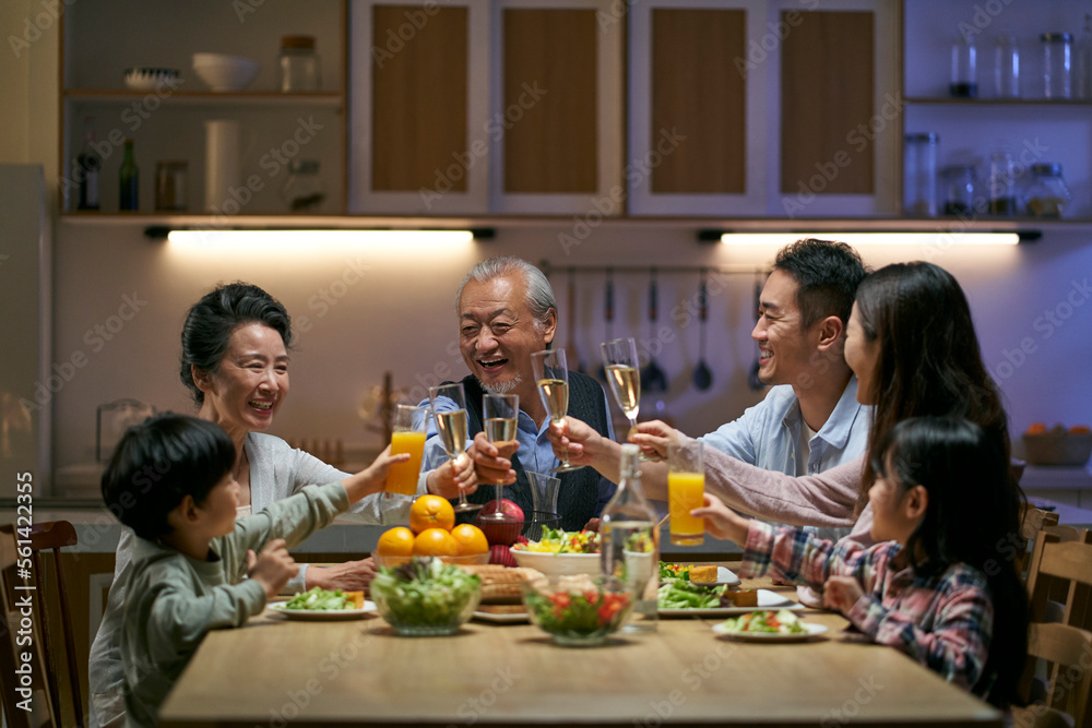three generation asian family toasting while having dinner together