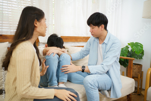 unhappy Asian family, critical problem of father and mother arguing with their daughter sitting and crying on sofa.