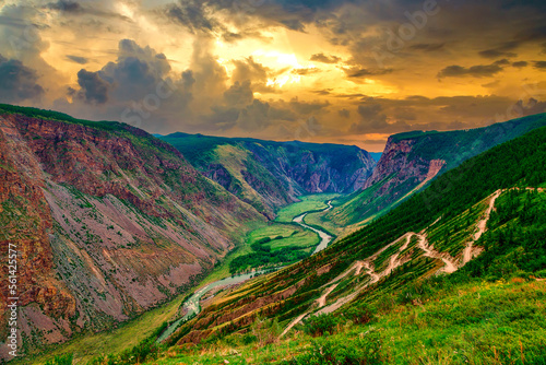 View of Katu Yaryk pass in Altai with a dramatic sky at sunset and serpentine road on one side against the background of a green juicy valley photo
