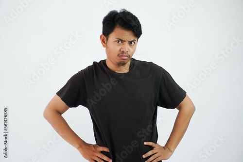 young Asian man wearing black t shirt stand hands at waist feels doubt at face isolated on white background