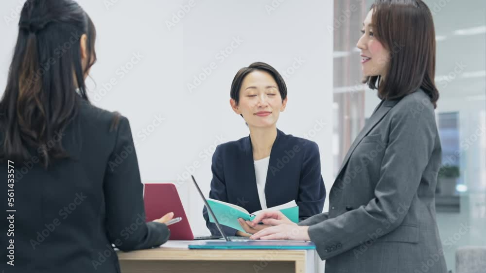 スタンディングミーティングする女性会社員グループ