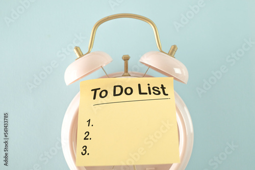 TO Do List word on sticky note with alarm clock over blue background use for To-do list,Time management,Productivity,business concept.
