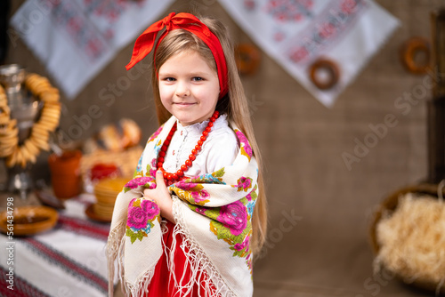 Portrait of little girl in national dress with Russian headscarf on shoulders. Maslenitsa concept. 