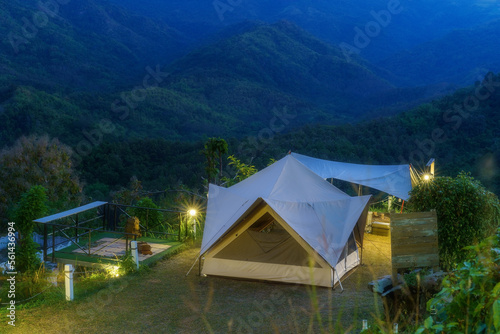 nature camping tent on mountain and holiday relax camp in tree forest or natural jungle on dusk twilight with warm white lamp with empty wooden signboard at khao kho phetchabun campground in thailand photo
