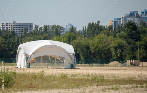 White large tents on the sand against the sky.