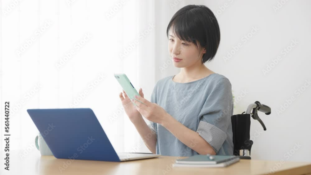 車椅子に座りながらスマートフォンを操作する若い女性　多様性社会イメージ	
