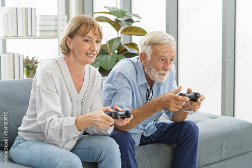 Happy senior couple, elderly family, Hand of caucasians mature, adult lover and retired husband, wife having fun, playing video game together, sitting cozy on sofa in living room at home, technology.