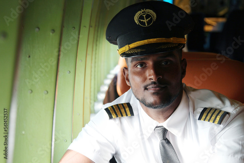 Young pilot in uniform smiling inside the plane.