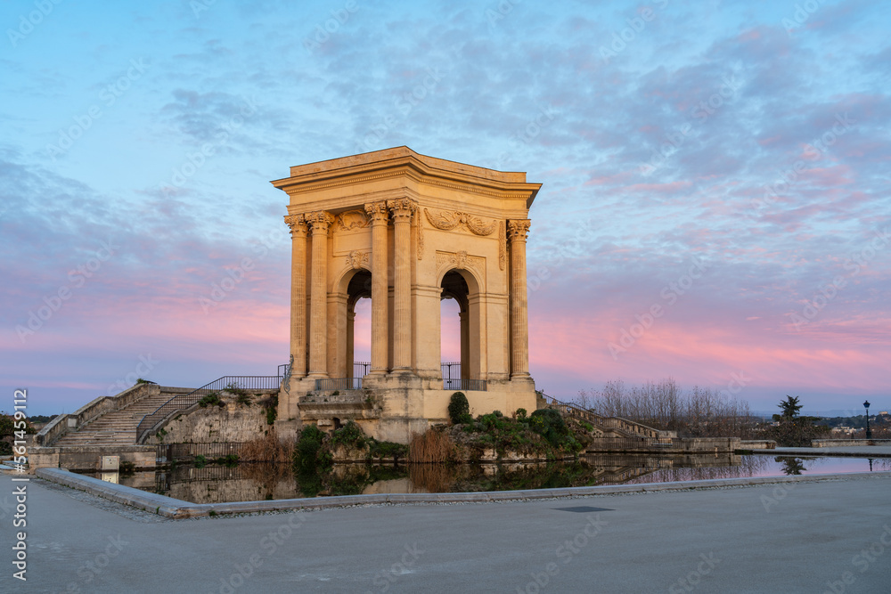 Colorful winter landscape view before sunrise of ancient water tower stone building and water pool in landmark Promenade du Peyrou garden, Montpellier, France