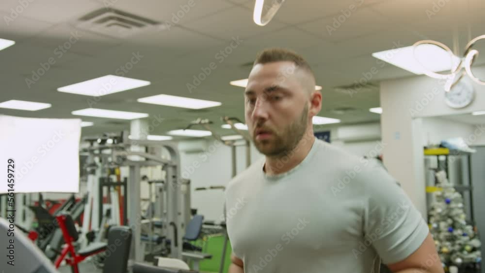 Young athletic man exercising and running on treadmill in sport gym Young athletic man exercising and running on treadmill in sport gym