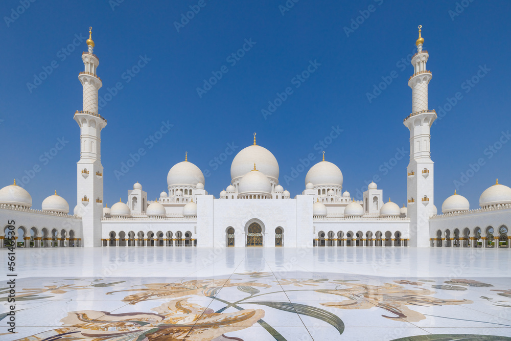 Fototapeta premium Symmetrical view of the main courtyard of the Sheik Zayed grand mosque in Abu Dhabi with the prayer hall flanked by minaret at the far end
