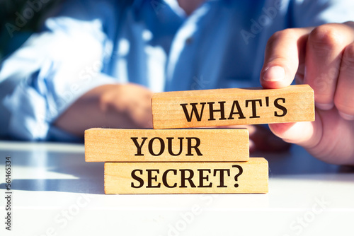 Closeup on businessman holding a wooden block with "What's your secret?"