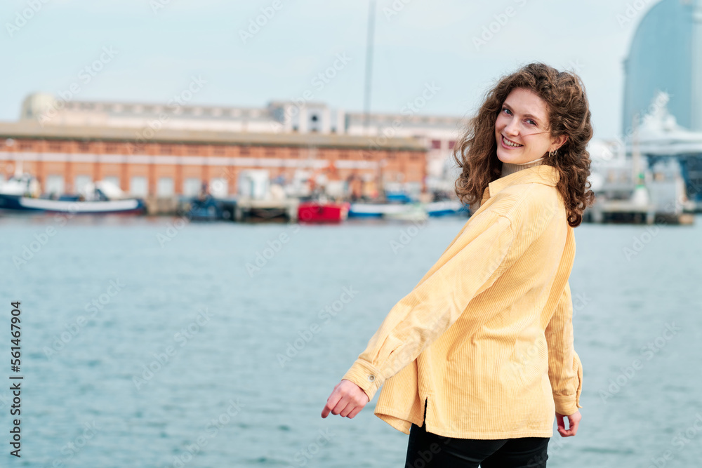 Young woman smiling while posing outdoors in the sea promenade.